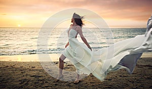 Beautiful young woman in white dress on a stormy beach