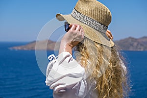 Beautiful young woman in white dress sunglasses and bikini straw hat looking at sea view in resort hotel villa