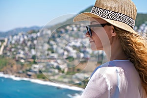 Beautiful young woman in white dress sunglasses and bikini straw hat looking at sea view in resort hotel villa