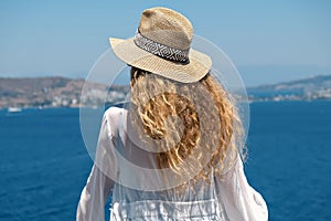 Beautiful young woman in white dress sunglasses and bikini straw hat looking at sea view in resort hotel villa