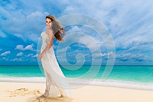 Beautiful young woman in white dress with umbrella on a tropical beach