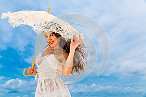 Beautiful young woman in white dress with umbrella on a tropical