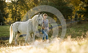 Beautiful young woman with a white horse in the country