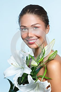 Beautiful young woman with with white lily flowers, female face