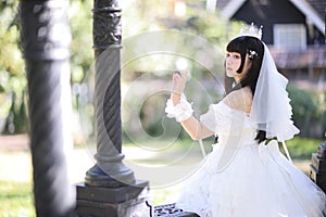 Beautiful young woman with white lolita dress with european garden Japanese fashion