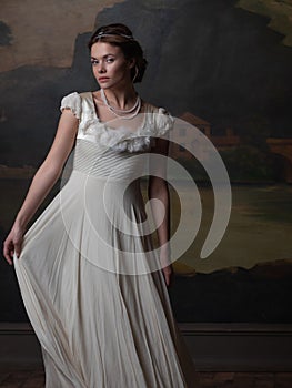 Beautiful young woman in a white long dress in the style of the 19th century.