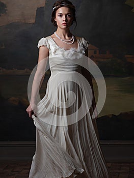 Beautiful young woman in a white long dress in the style of the 19th century. photo
