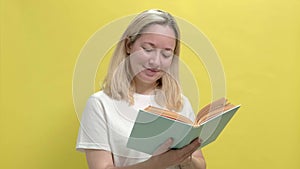 Beautiful young woman in a white T-shirt looks in an open book in her hands