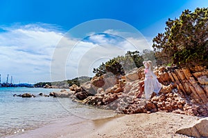 Beautiful woman sitting on a rock ocean shore