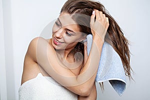 Beautiful young woman wipes her hairs with a towel.