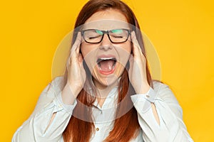 Beautiful young woman worker with long hair and glasses suffering from a headache or migraine. Hands on your head.