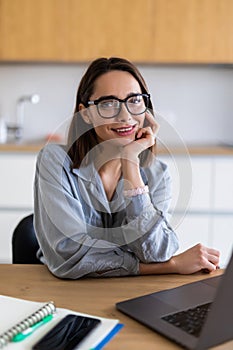 Beautiful young woman working on her laptop in her office at home
