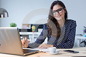 Beautiful young woman working with laptop in her office.