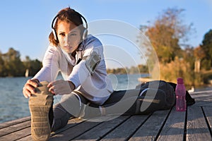 Beautiful young woman working out outside by the water