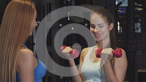 Beautiful young woman working out with personal trainer at the gym