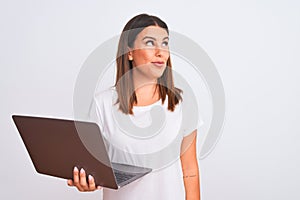 Beautiful young woman working using computer laptop over white background smiling looking to the side and staring away thinking