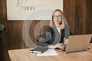 Beautiful young woman working using laptop computer, looking out the window distractedly, good responsible office worker