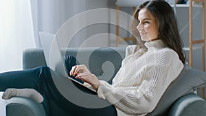 Beautiful Young Woman Works on Laptop Computer while Sitting on the Chair. Sensual Girl Wearing