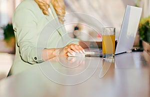 Beautiful young woman works at a laptop and sits in a cafe with a glass of orange juice