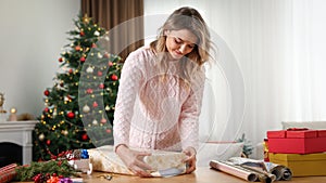 Beautiful young woman wrapping Christmas gift at home