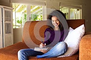 Beautiful young woman writing ideas in book