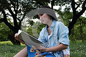 Beautiful young woman writing outdoors in a park