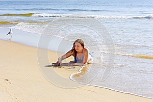 Beautiful young woman writing the word LOVE on the sand