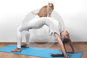 Beautiful young woman in yoga posing with cat. Fitness and pilates