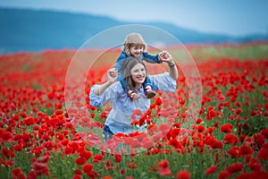 Beautiful young woman with child girl in poppy field. happy family having fun in nature. outdoor portrait in poppies. mother with