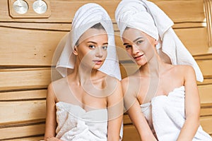 beautiful young women covered with towels relxing in sauna and looking