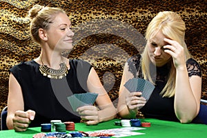 Beautiful young women playing cards or poker in a backroom or casino