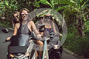 beautiful young women riding motorbikes and smiling at camera