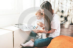 Beautiful young woman with small child sit near the window