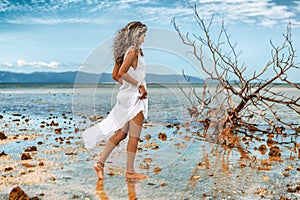 Beautiful ypung stylish woman in white dress on the beach