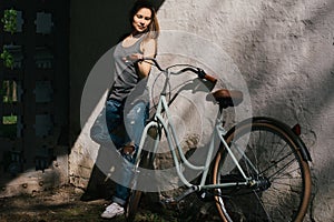 Beautiful yuong female in denim standing with bicycle