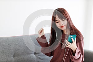 Beautifull Asian woman listening music form smart phone in her bedroom. Stay at home, coronavirus covid-19