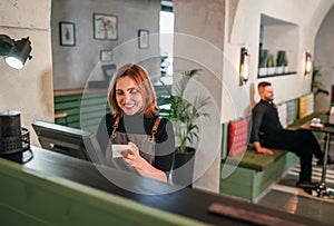 Beautifull smiling waitress dressed black uniform processing customer orders using point of sale order terminal system touch