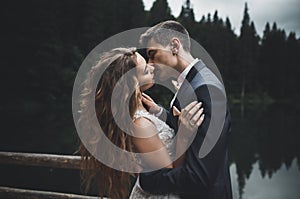 Beautifull wedding couple kissing and embracing near mountain with perfect view