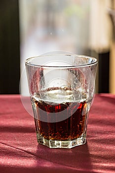 A beautifully backlit glass of red soft drink on a restaurant table