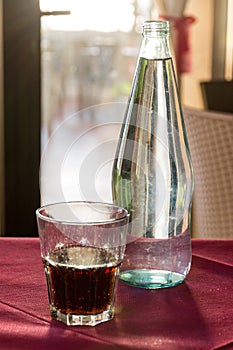 A beautifully backlit glass of red soft drink on a restaurant table