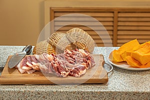 Beautifully cut slices of fresh fatty meat for further cooking on a background of bamboo utensils