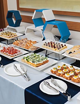 Beautifully decorated banquet catering table, with variety of with different food snacks appetizers on corporate birthday party