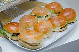 Beautifully decorated catering banquet table with different hamburgers burgers sandwiches on a plate on corporate birthday . Mini