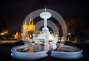 Beautifully decorated historic fountain with an old city gate in the background