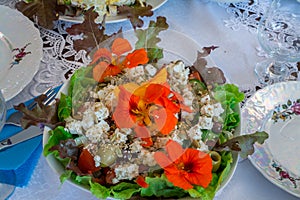 Beautifully decorated home made  salads with edible flowers  on table with different food snacks  party