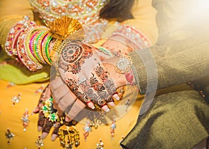 Beautifully decorated Indian bride hands with the groom.