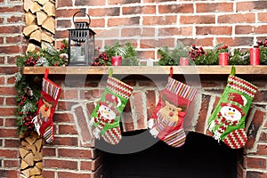 Beautifully decorated Santa Christmas socks hanging on a fireplace in brick wall waiting for presents, close-up view