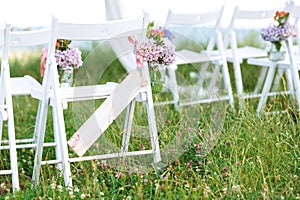 Beautifully decorated white chairs for wedding reception outdoors. Wedding decor. Close up