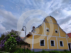Beautifully decorated yellow rural farmstead house with some blooming flowers on the left side
