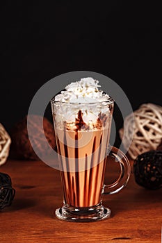 Beautifully designed latte macchiato coffee with whipped cream, in a high transparent glass, on a dark background